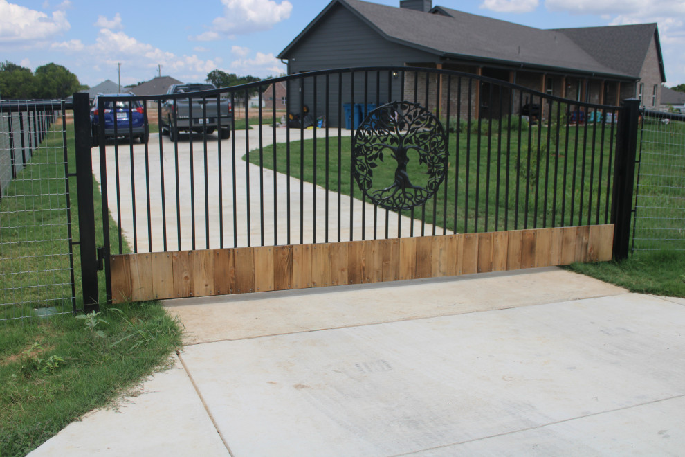 This is an example of a large front yard driveway in Dallas with with a gate and a metal fence.