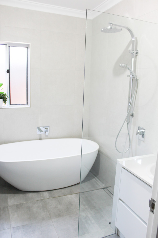 Photo of a mid-sized modern kids wet room bathroom in Perth with flat-panel cabinets, white cabinets, a freestanding tub, gray tile, porcelain tile, grey walls, porcelain floors, a vessel sink, engineered quartz benchtops, grey floor, an open shower, white benchtops, a single vanity and a freestanding vanity.