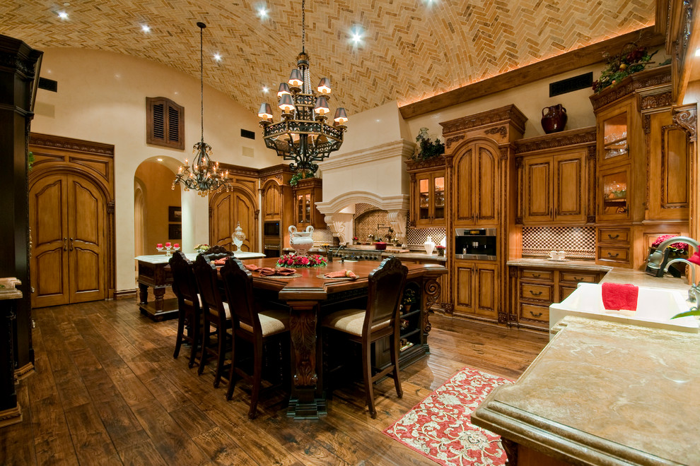 Eat-in kitchen - huge transitional u-shaped medium tone wood floor eat-in kitchen idea in Phoenix with a farmhouse sink, raised-panel cabinets, medium tone wood cabinets, granite countertops, beige backsplash, mosaic tile backsplash, stainless steel appliances and two islands