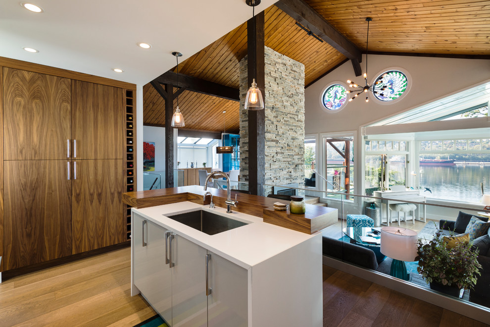 Inspiration for a mid-sized l-shaped light wood floor and brown floor open concept kitchen remodel in Vancouver with an undermount sink, flat-panel cabinets, white cabinets, quartz countertops, white backsplash, ceramic backsplash, stainless steel appliances and an island