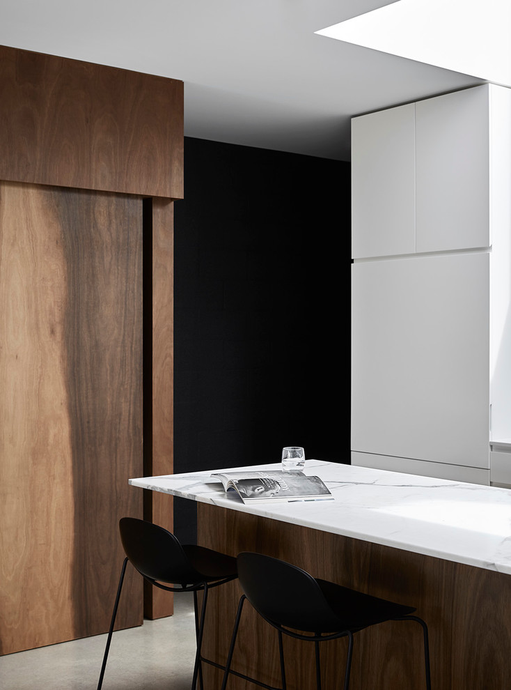 Design ideas for a mid-sized contemporary u-shaped eat-in kitchen in Melbourne with an undermount sink, flat-panel cabinets, white cabinets, marble benchtops, white splashback, mosaic tile splashback, stainless steel appliances, concrete floors and with island.