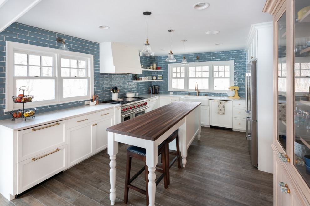 Idéer för vintage vitt u-kök, med en rustik diskho, luckor med infälld panel, vita skåp, blått stänkskydd, rostfria vitvaror, mörkt trägolv, en köksö och brunt golv