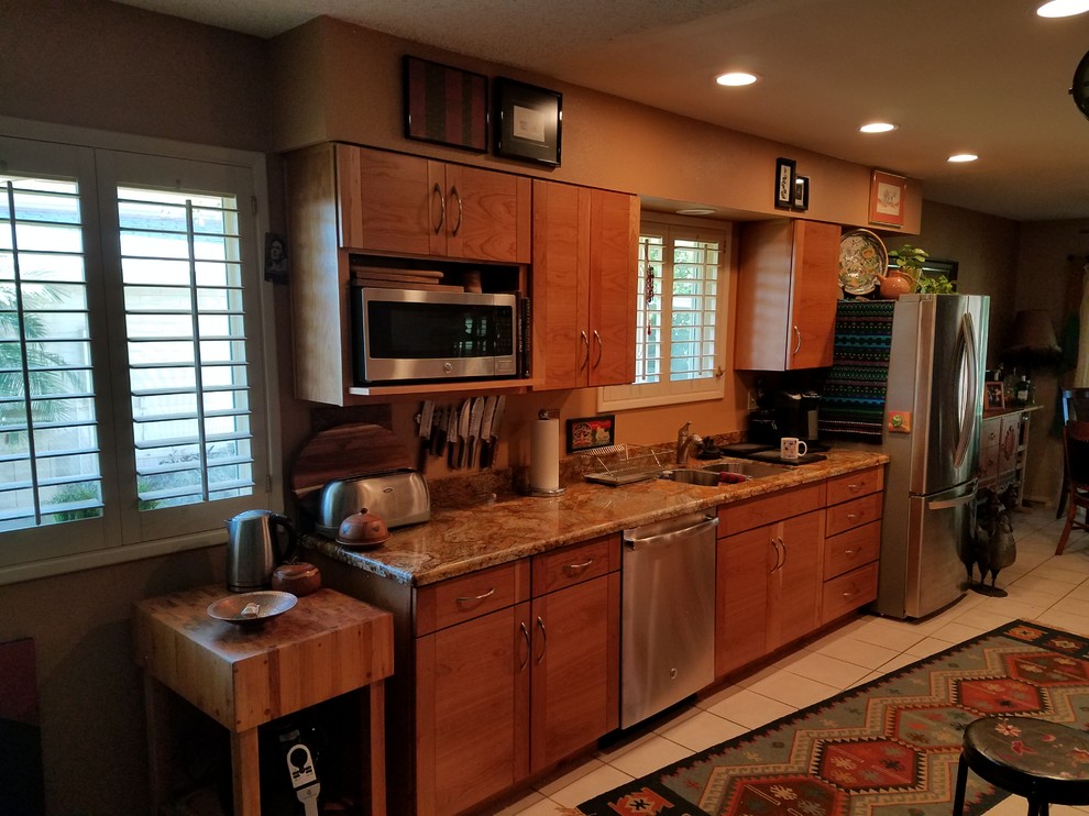 Example of a large transitional galley ceramic tile kitchen design in Phoenix with a double-bowl sink, flat-panel cabinets, medium tone wood cabinets, granite countertops, stainless steel appliances and an island