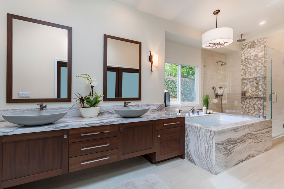 Photo of a mid-sized transitional master bathroom in Los Angeles with louvered cabinets, dark wood cabinets, an undermount tub, a corner shower, pebble tile, beige walls, porcelain floors, a vessel sink, engineered quartz benchtops, beige floor, a hinged shower door and multi-coloured benchtops.