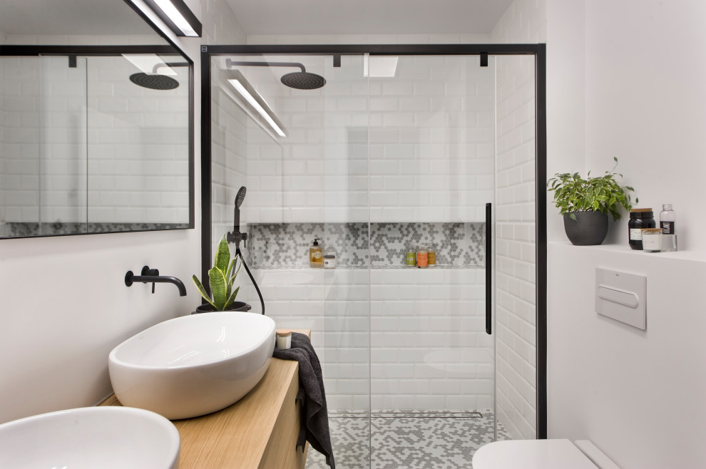 Design ideas for a contemporary 3/4 bathroom in Barcelona with flat-panel cabinets, light wood cabinets, an alcove shower, white tile, subway tile, white walls, mosaic tile floors, a vessel sink, wood benchtops, grey floor, a sliding shower screen, beige benchtops, a niche and a double vanity.