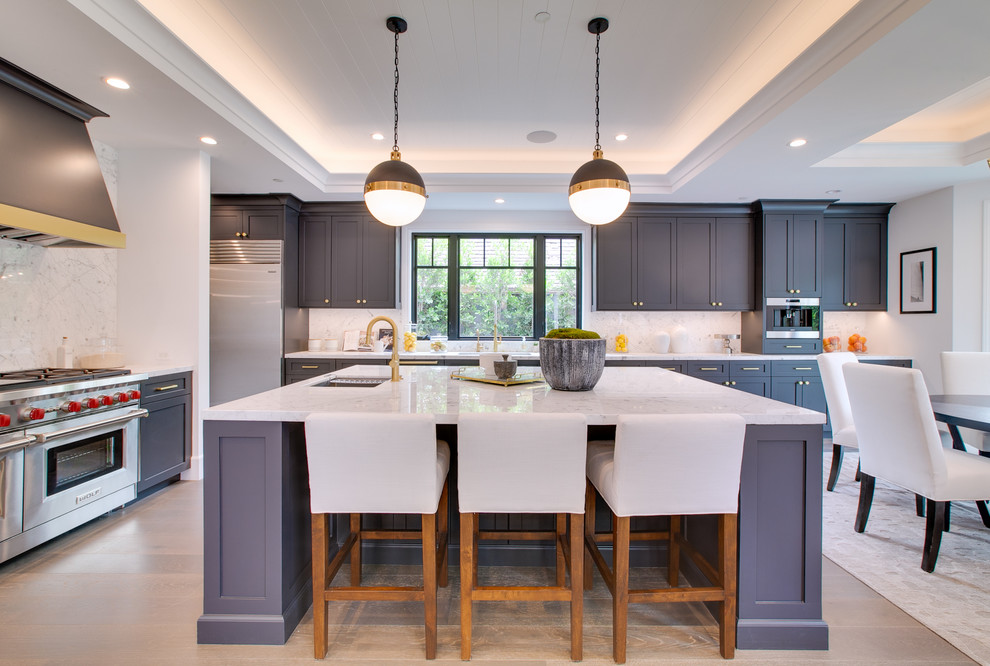 Inspiration for a transitional l-shaped beige floor eat-in kitchen remodel in Los Angeles with an undermount sink, shaker cabinets, gray cabinets, white backsplash, stainless steel appliances, an island and white countertops