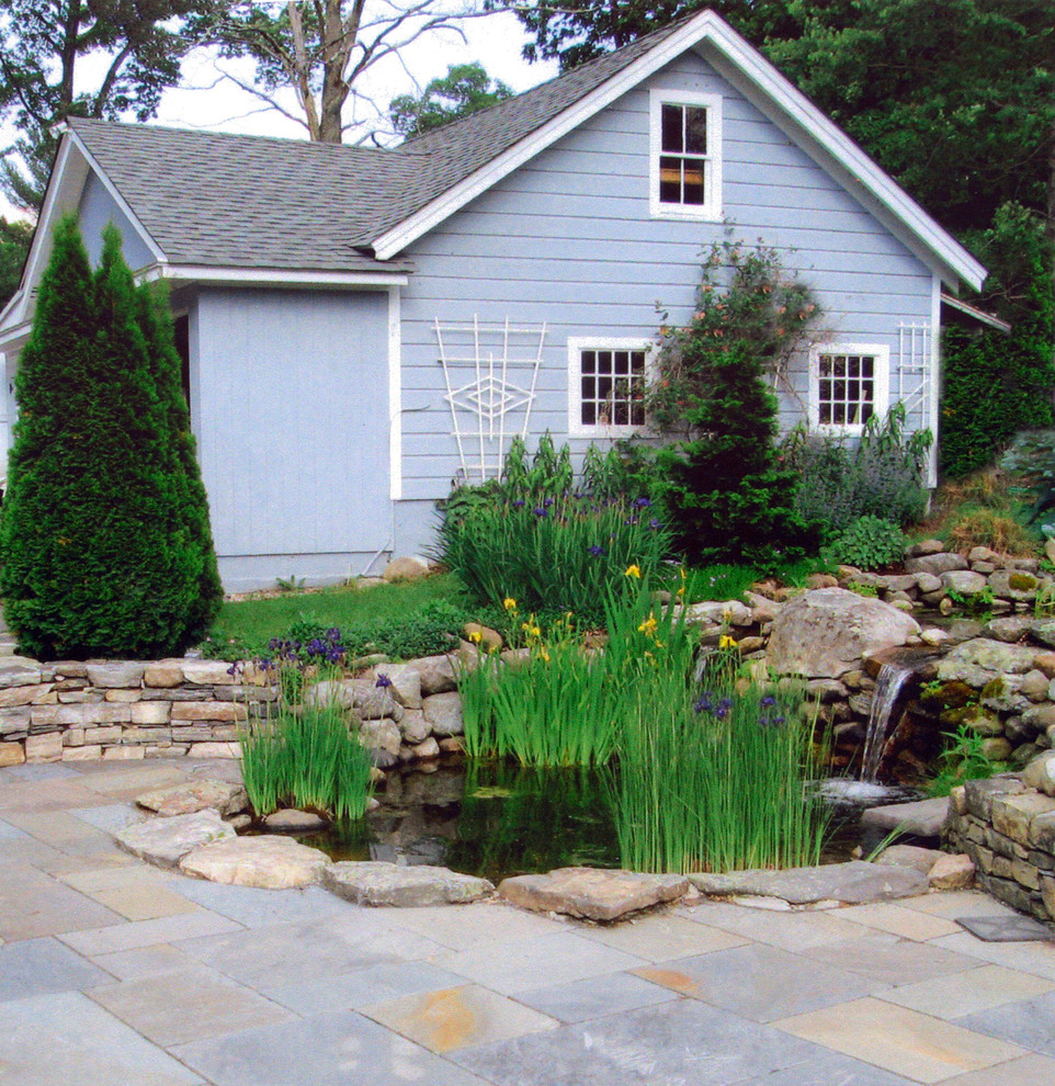 Large traditional backyard garden in New York with with pond.