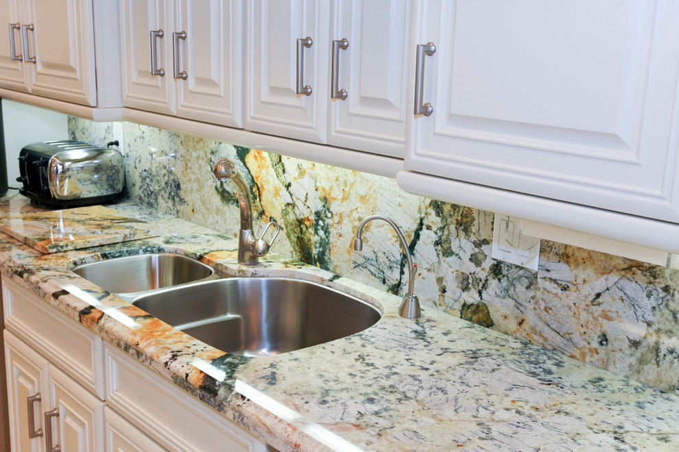 Eat-in kitchen - large transitional galley ceramic tile eat-in kitchen idea in Miami with a double-bowl sink, raised-panel cabinets, white cabinets, granite countertops, multicolored backsplash, stone slab backsplash, stainless steel appliances and an island