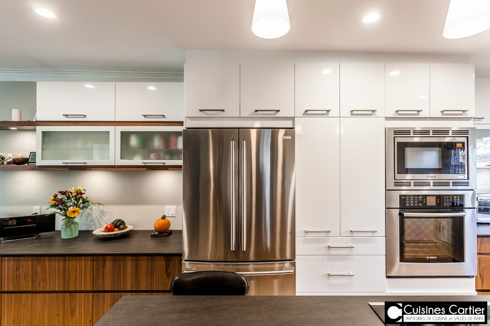 Eat-in kitchen - large transitional galley medium tone wood floor eat-in kitchen idea in Montreal with an undermount sink, flat-panel cabinets, dark wood cabinets, quartzite countertops, white backsplash, mosaic tile backsplash, stainless steel appliances and an island