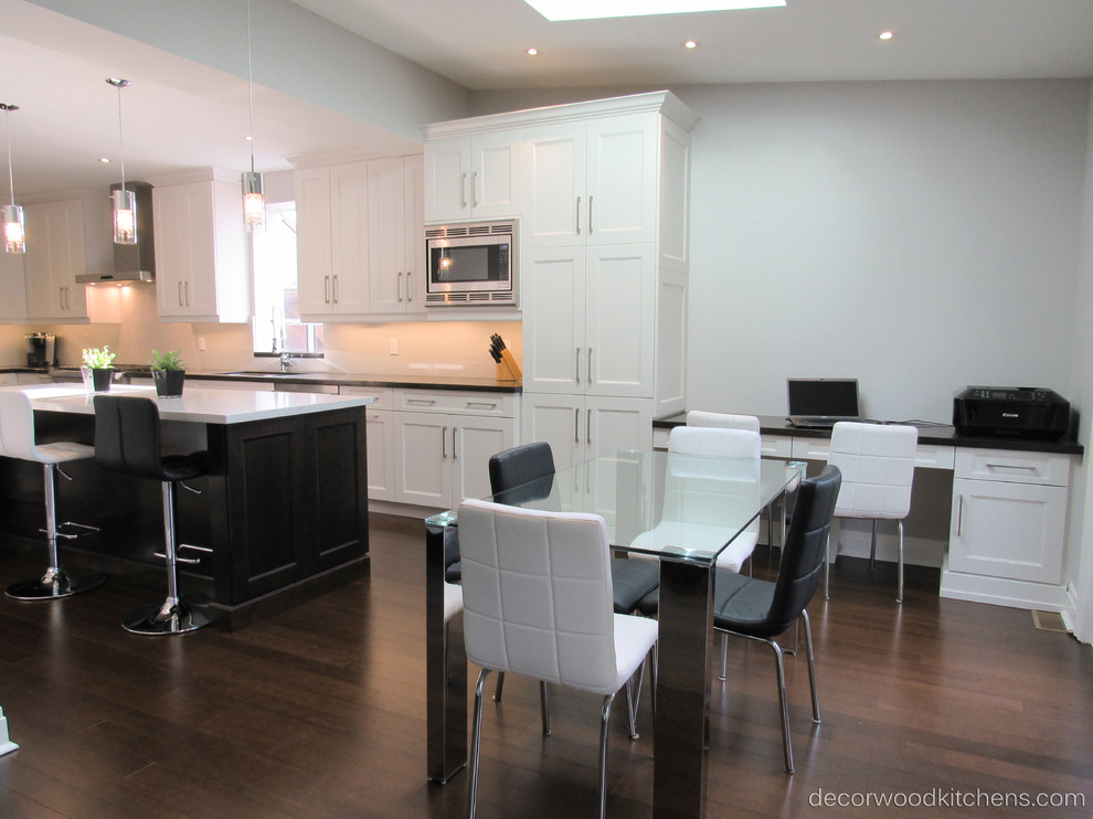 Large transitional l-shaped dark wood floor enclosed kitchen photo in Toronto with an undermount sink, shaker cabinets, white cabinets, quartz countertops, white backsplash, stone slab backsplash, stainless steel appliances and an island