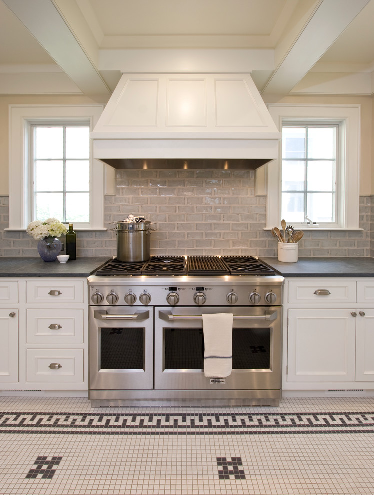 Inspiration for a mid-sized traditional u-shaped eat-in kitchen in New York with an integrated sink, shaker cabinets, white cabinets, soapstone benchtops, green splashback, ceramic splashback, stainless steel appliances and limestone floors.
