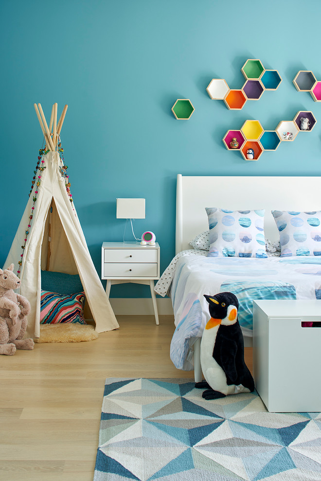 Design ideas for a large modern gender-neutral kids' bedroom for kids 4-10 years old in San Francisco with blue walls and light hardwood floors.