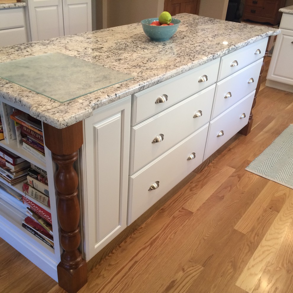 Example of a transitional u-shaped medium tone wood floor eat-in kitchen design in Boston with an undermount sink, raised-panel cabinets, white cabinets, granite countertops, blue backsplash, glass tile backsplash, stainless steel appliances and an island