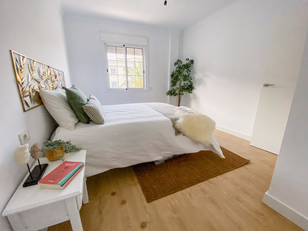 Modelo de dormitorio principal grande con paredes blancas, suelo de madera en tonos medios y suelo beige