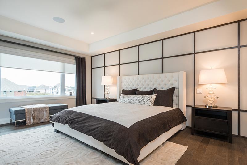 This is an example of a large modern master bedroom in Toronto with beige walls, dark hardwood floors and no fireplace.