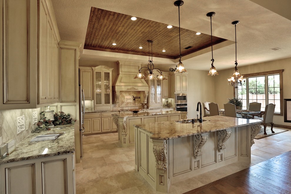 Inspiration for a mid-sized mediterranean eat-in kitchen in Dallas with an undermount sink, shaker cabinets, granite benchtops, beige splashback, stone tile splashback, stainless steel appliances, porcelain floors and multiple islands.