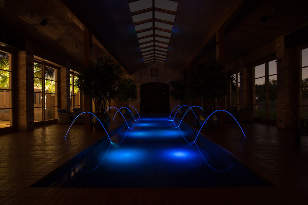 Photo of a large traditional indoor rectangular pool in Austin with a water feature and brick pavers.