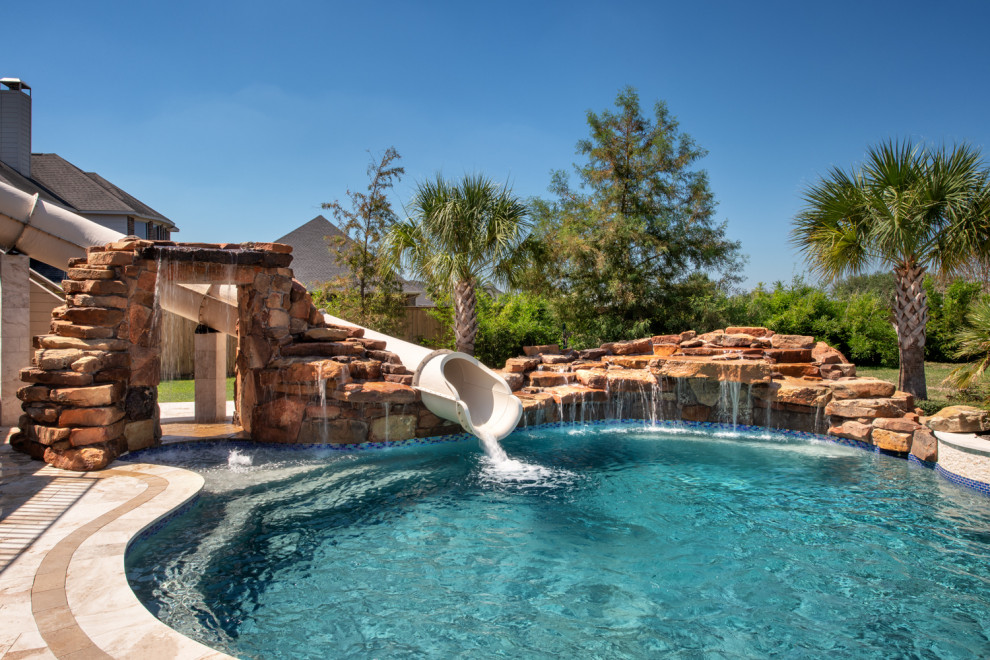 Esempio di una grande piscina chic personalizzata dietro casa con un acquascivolo e pavimentazioni in pietra naturale
