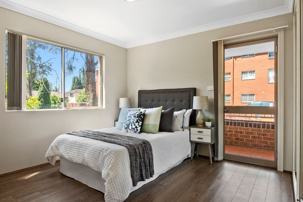 This is an example of a small contemporary master bedroom in Sydney with beige walls, dark hardwood flooring and brown floors.