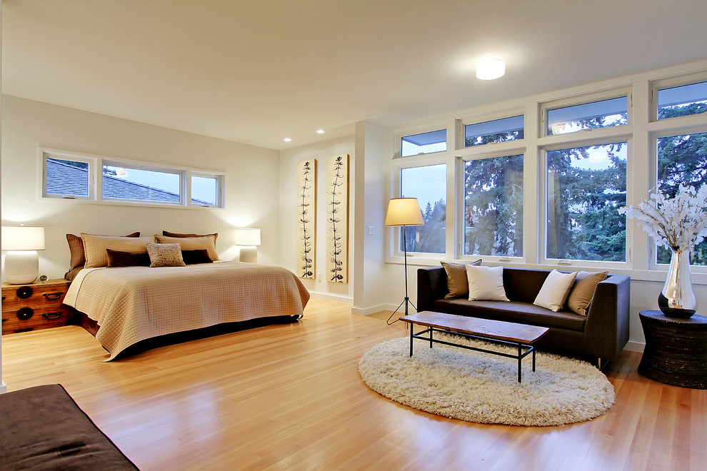 This is an example of a contemporary master bedroom in Seattle with white walls, light hardwood floors and no fireplace.