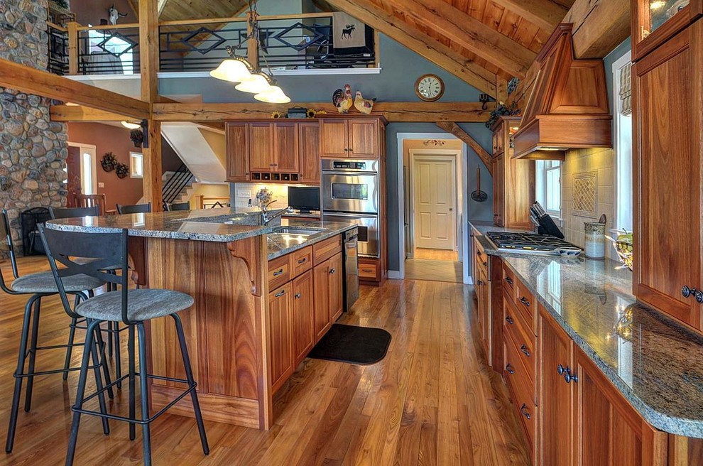 Eat-in kitchen - mid-sized rustic galley medium tone wood floor eat-in kitchen idea in Milwaukee with an undermount sink, recessed-panel cabinets, medium tone wood cabinets, white backsplash, ceramic backsplash and an island
