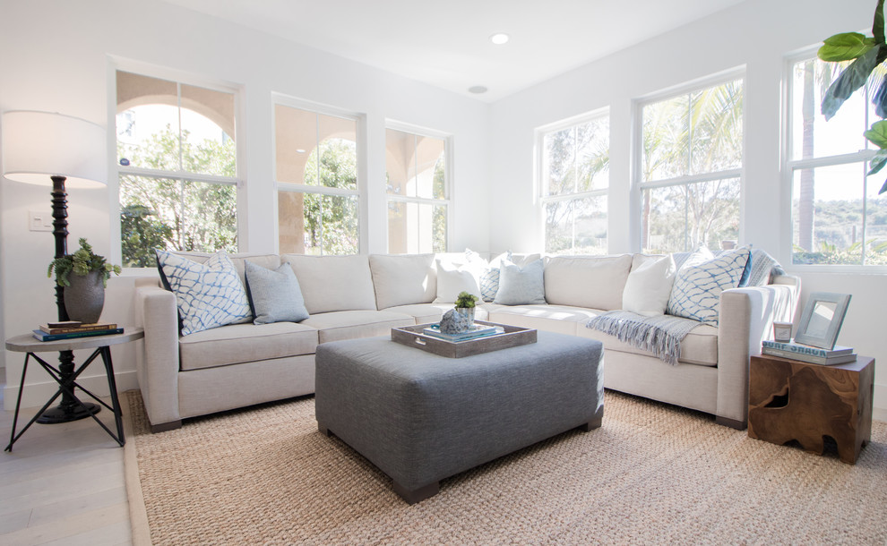 Design ideas for a beach style living room in Orange County with white walls, light hardwood floors and beige floor.