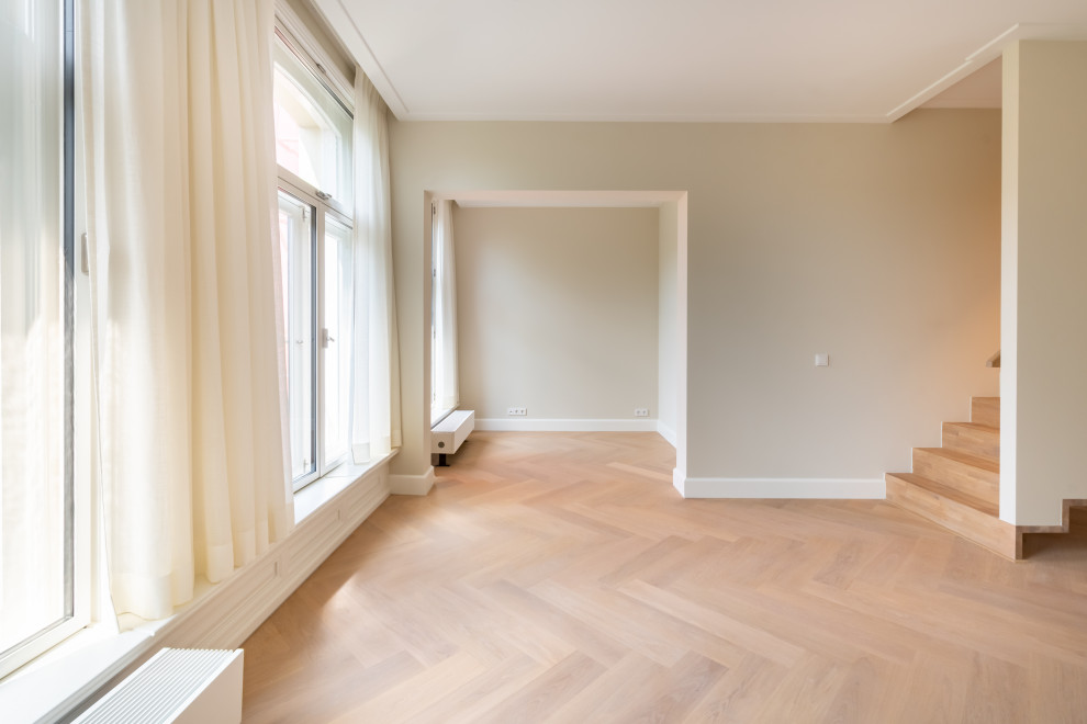 Foto de salón actual con paredes beige, suelo de madera clara y marco de chimenea de piedra