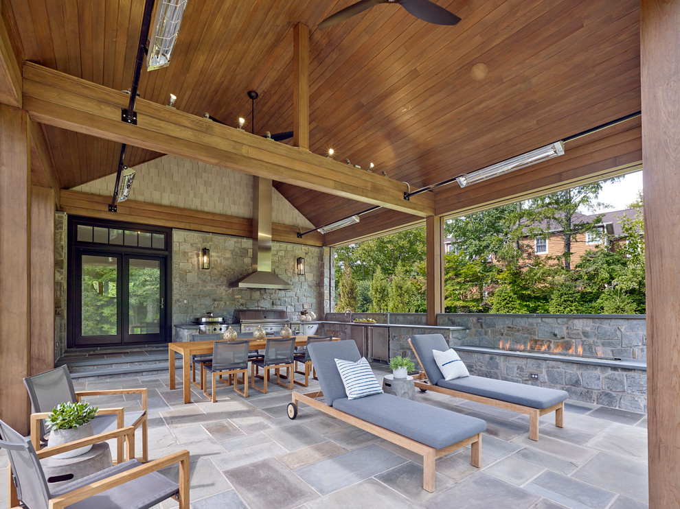This is an example of an expansive transitional backyard screened-in verandah in New York with natural stone pavers and a roof extension.