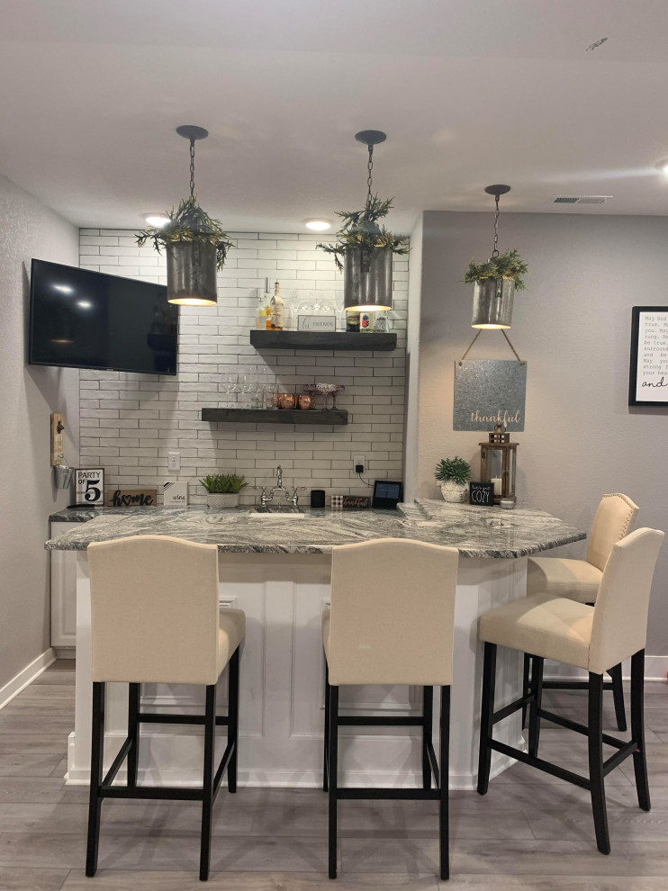 Design ideas for a mid-sized modern l-shaped seated home bar in Denver with an undermount sink, raised-panel cabinets, white cabinets, quartz benchtops, white splashback, brick splashback, vinyl floors, grey floor and grey benchtop.