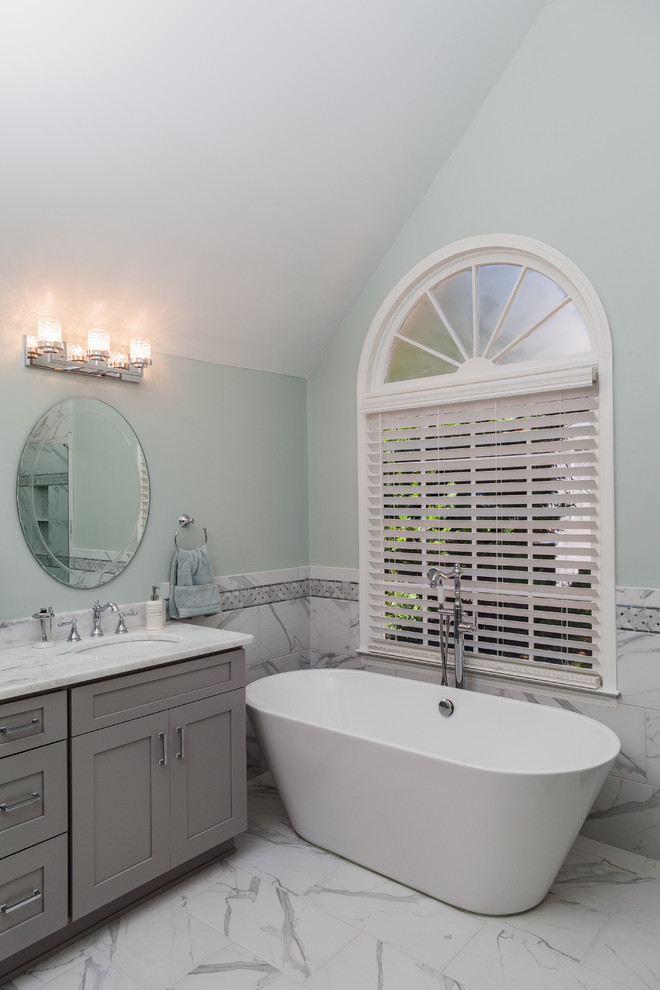 This is an example of a large transitional master bathroom in Atlanta with shaker cabinets, grey cabinets, a freestanding tub, a double shower, a two-piece toilet, white tile, marble, green walls, marble floors, an undermount sink, quartzite benchtops, white floor, a hinged shower door and white benchtops.