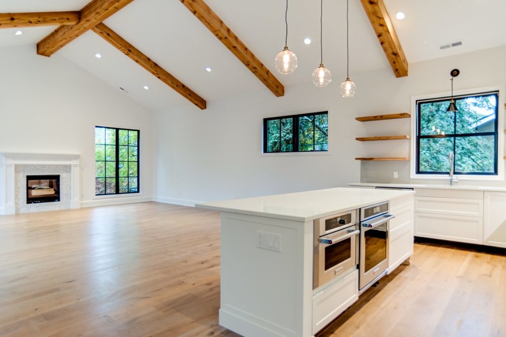 Eat-in kitchen - mid-sized transitional u-shaped medium tone wood floor eat-in kitchen idea in Seattle with a double-bowl sink, raised-panel cabinets, white cabinets, soapstone countertops, white backsplash, stone slab backsplash, stainless steel appliances and an island
