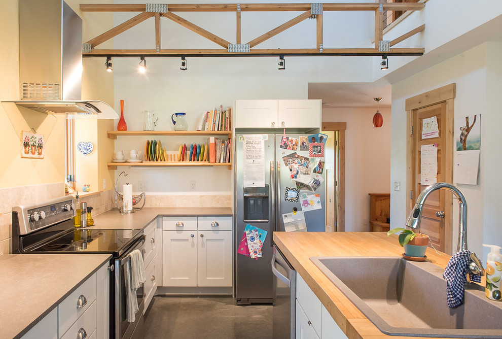 Open concept kitchen - mid-sized transitional l-shaped concrete floor and gray floor open concept kitchen idea with a drop-in sink, shaker cabinets, white cabinets, wood countertops, yellow backsplash, stainless steel appliances, an island and brown countertops