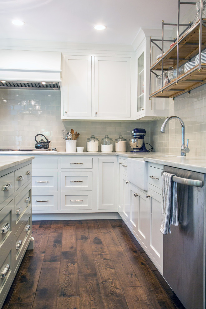 Inspiration for a transitional l-shaped eat-in kitchen in Philadelphia with a farmhouse sink, shaker cabinets, white cabinets, white splashback, subway tile splashback, stainless steel appliances, dark hardwood floors and with island.