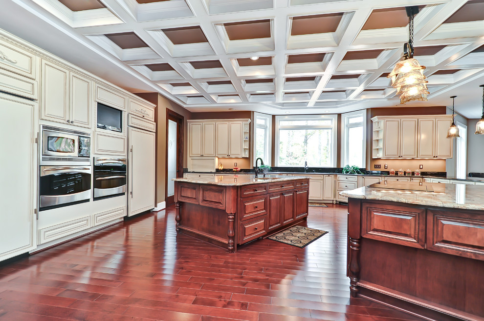 This is an example of a traditional u-shaped eat-in kitchen with an undermount sink, raised-panel cabinets and brown cabinets.