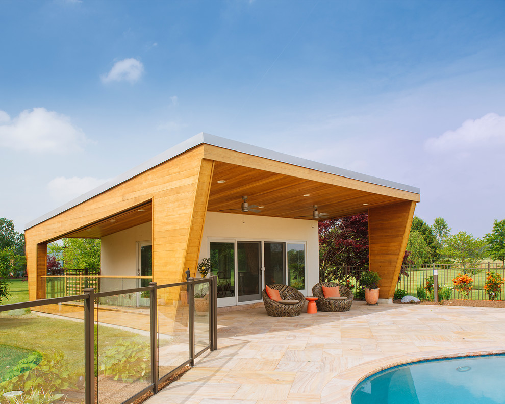 This is an example of a large contemporary backyard kidney-shaped pool in Philadelphia with a pool house and natural stone pavers.
