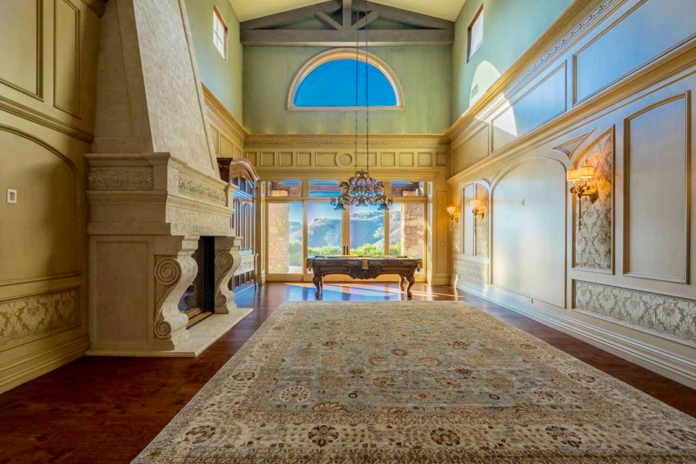 Design ideas for an expansive classic enclosed games room in San Diego with a game room, green walls, medium hardwood flooring, a standard fireplace, a stone fireplace surround, brown floors, a vaulted ceiling and wainscoting.