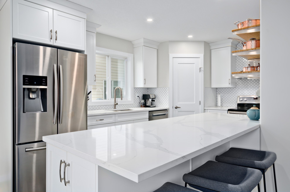 Inspiration for a mid-sized transitional u-shaped eat-in kitchen in Calgary with a double-bowl sink, shaker cabinets, white cabinets, quartzite benchtops, white splashback, mosaic tile splashback, stainless steel appliances, vinyl floors, with island and white benchtop.