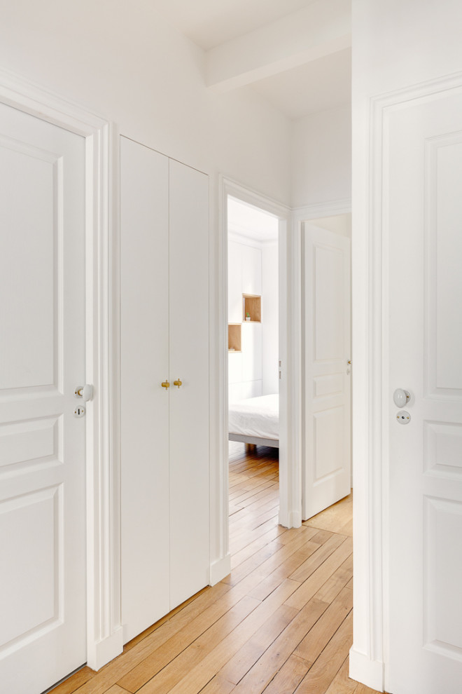 Cette image montre un couloir design avec un mur blanc, parquet foncé et un sol marron.