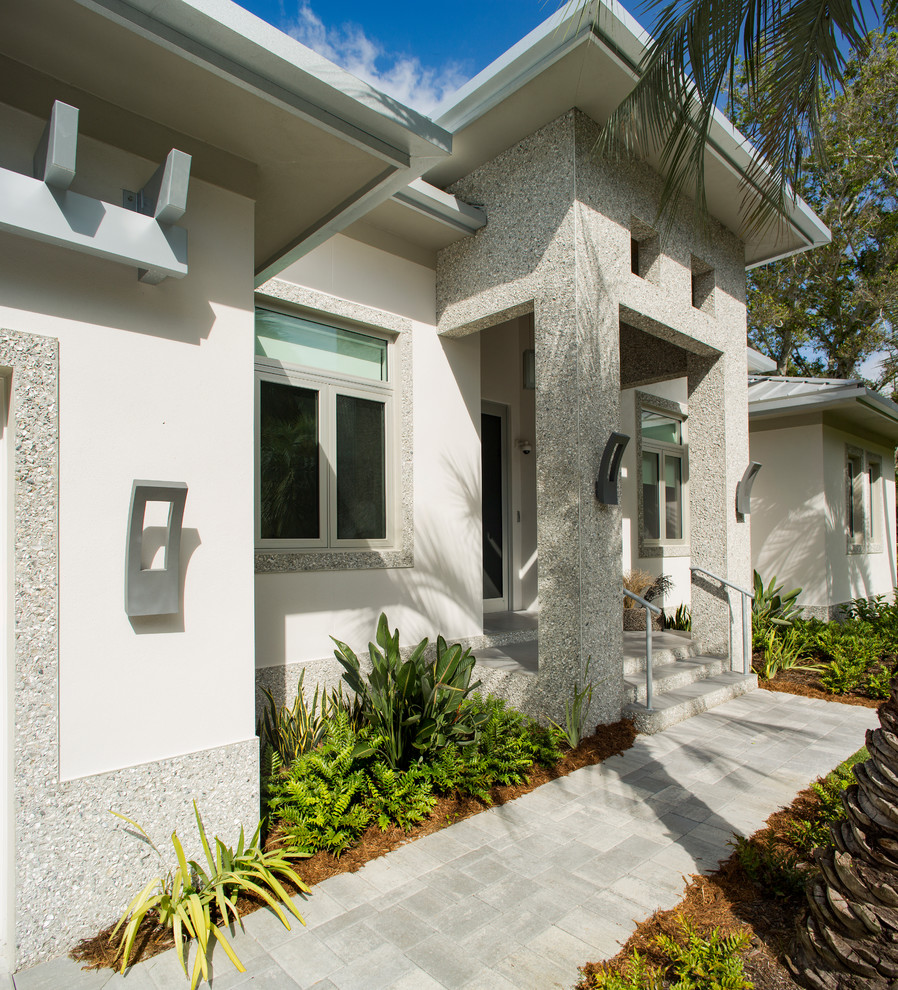 Photo of a mid-sized contemporary one-storey stucco grey house exterior in Tampa with a metal roof.