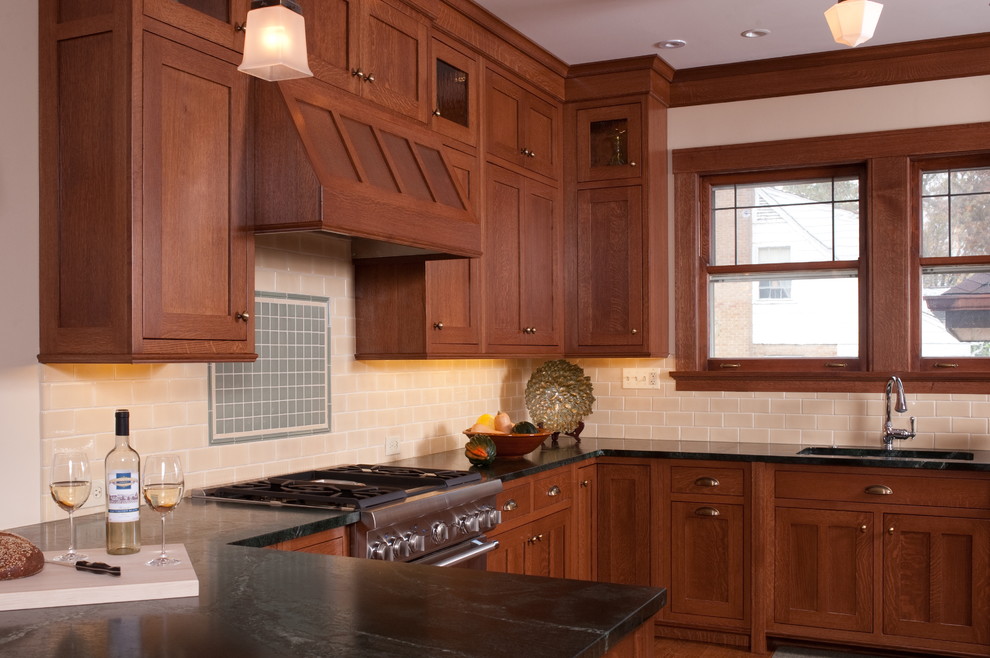 Photo of an arts and crafts u-shaped eat-in kitchen in Chicago with shaker cabinets, medium wood cabinets, soapstone benchtops, beige splashback, subway tile splashback, stainless steel appliances and an undermount sink.