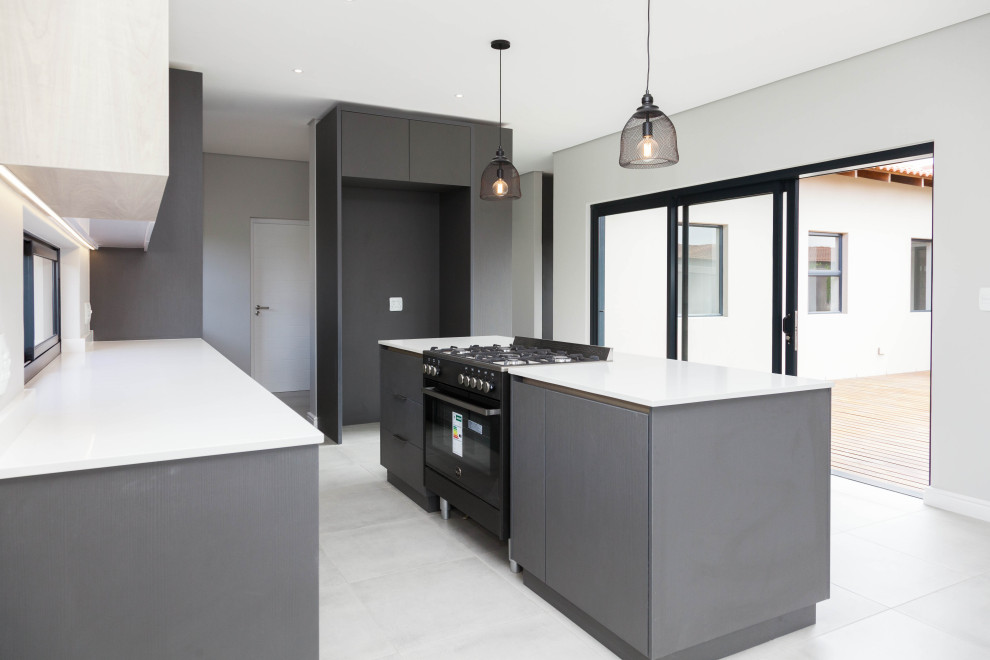 Example of a minimalist porcelain tile and gray floor kitchen design with gray cabinets, quartz countertops and white countertops