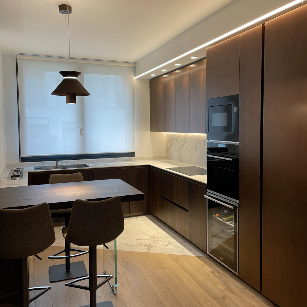 This is an example of a medium sized contemporary u-shaped enclosed kitchen in Milan with a single-bowl sink, beaded cabinets, medium wood cabinets, marble worktops, white splashback, marble splashback, black appliances, marble flooring, an island, white floors, white worktops and a drop ceiling.