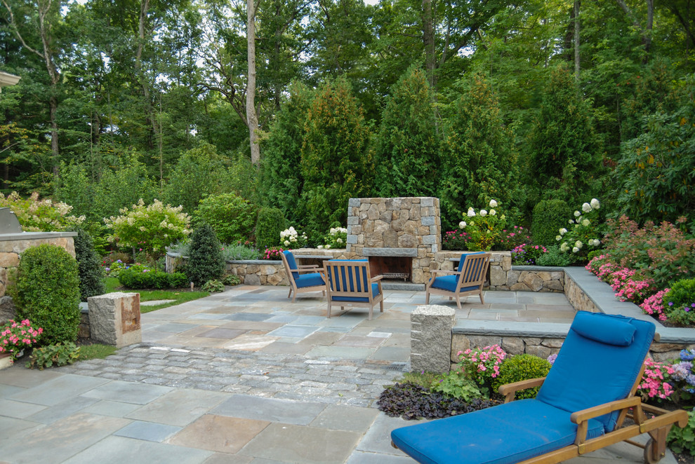 This is an example of a mid-sized traditional backyard patio in Boston with natural stone pavers and a fire feature.