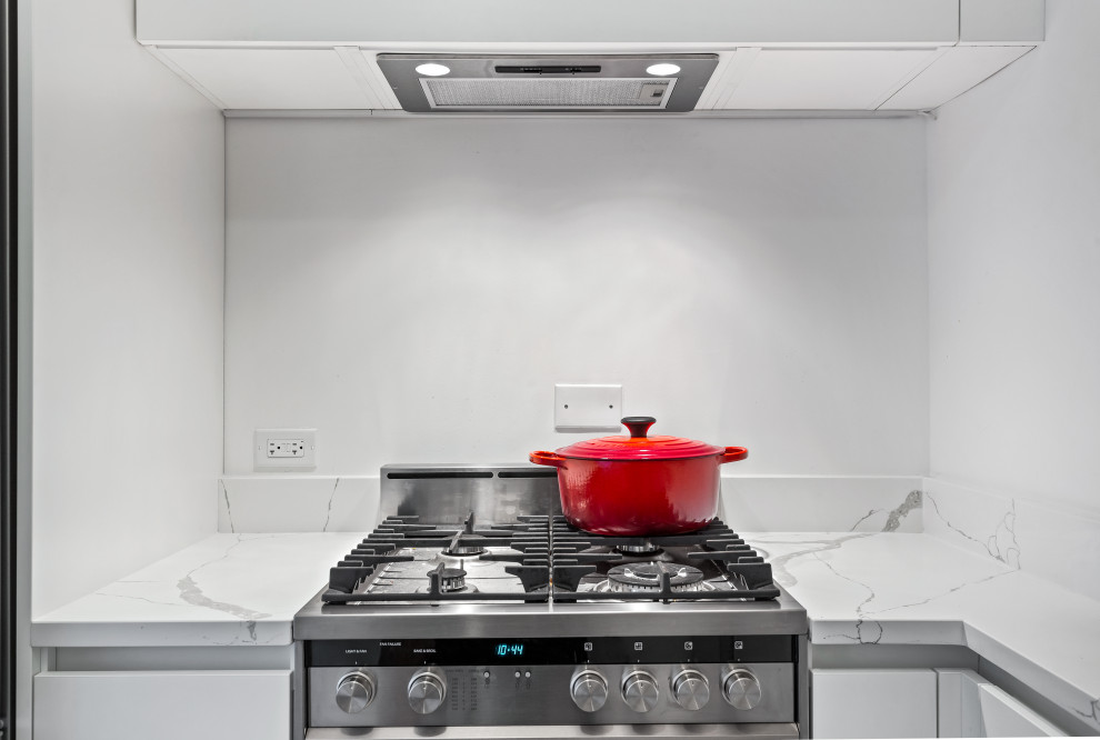 Inspiration for a mid-sized transitional l-shaped light wood floor enclosed kitchen remodel in Chicago with an undermount sink, flat-panel cabinets, white cabinets, marble countertops, white backsplash, subway tile backsplash, stainless steel appliances, no island and white countertops