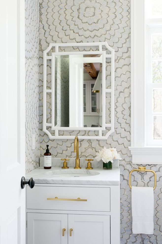 Design ideas for a beach style powder room in New York with shaker cabinets, white cabinets, multi-coloured walls, an undermount sink and white benchtops.