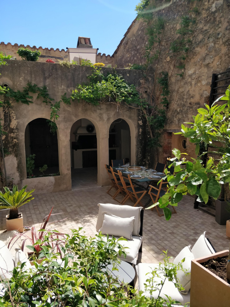 Inspiration for a mid-sized mediterranean backyard patio in Marseille with a container garden, natural stone pavers and an awning.