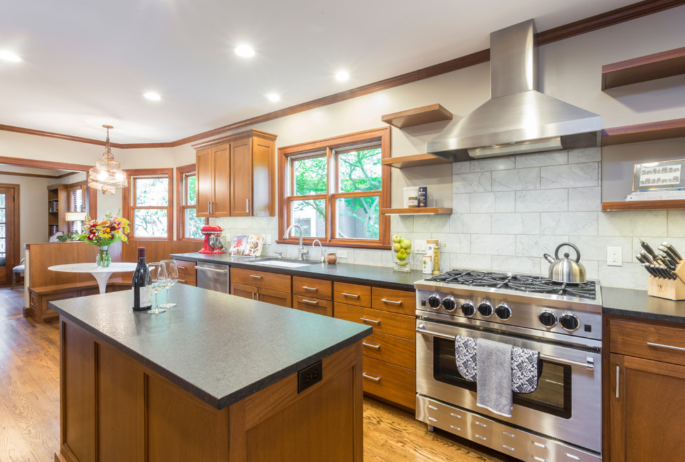 Large transitional u-shaped medium tone wood floor and brown floor eat-in kitchen photo in Portland with an undermount sink, shaker cabinets, medium tone wood cabinets, soapstone countertops, marble backsplash, stainless steel appliances, an island, black countertops and white backsplash