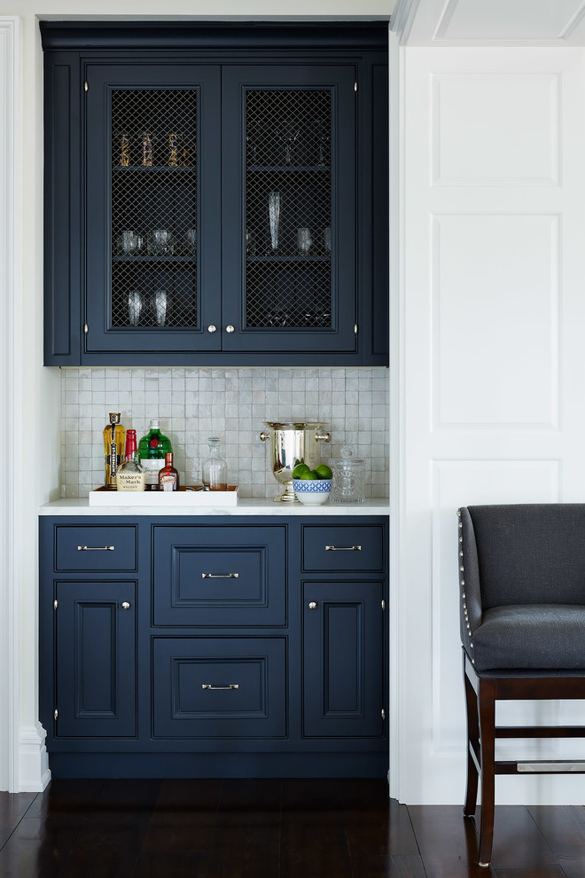 Inspiration for a small traditional single-wall home bar in Jacksonville with no sink, recessed-panel cabinets, blue cabinets, white splashback, mosaic tile splashback, dark hardwood floors and white benchtop.