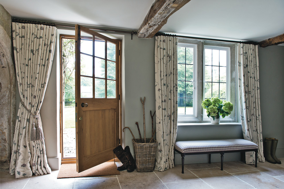 This is an example of a country entryway in Dorset with grey walls, limestone floors, a single front door and a medium wood front door.