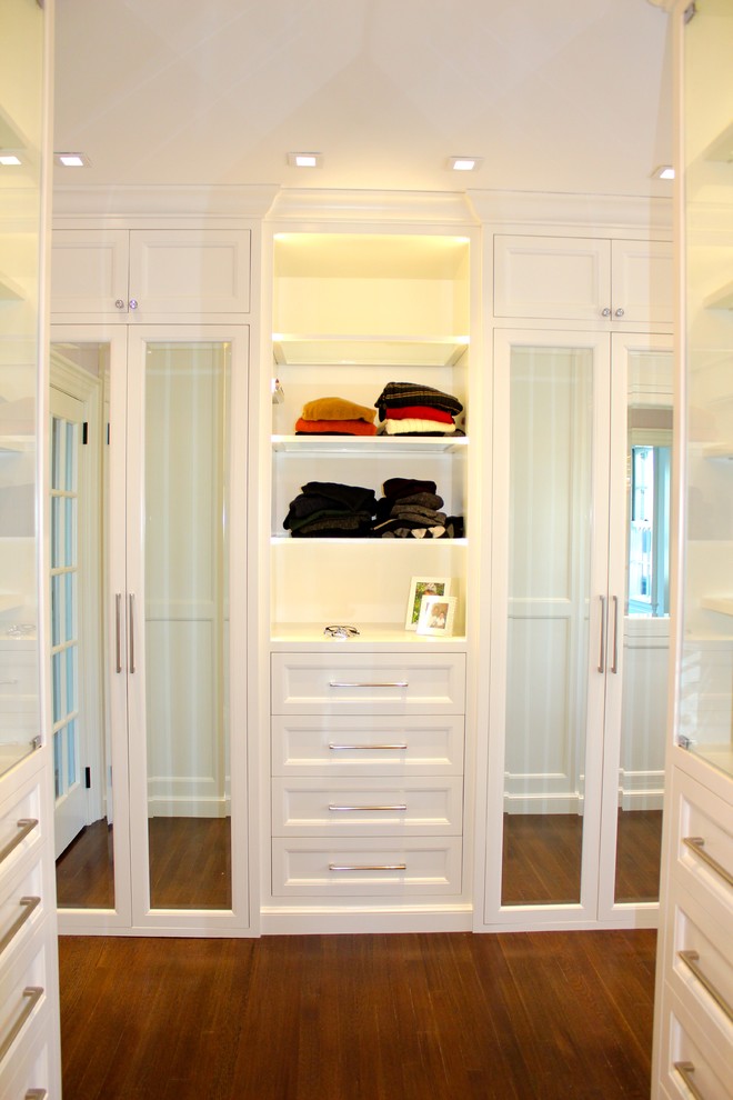 Photo of a large contemporary gender-neutral walk-in wardrobe in New York with recessed-panel cabinets, white cabinets and dark hardwood floors.
